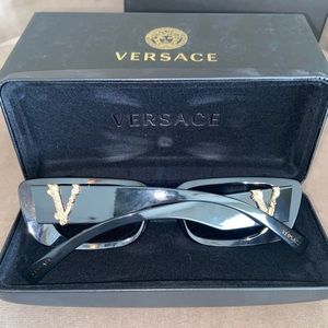 Black Versace sunglasses with gold “V” logo on sides